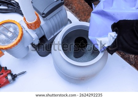 Assembling components of pool filtration system on works day in backyard setting, near swimming pool