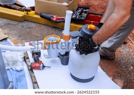 Assembling components of pool filtration system on works day in backyard setting, near swimming pool