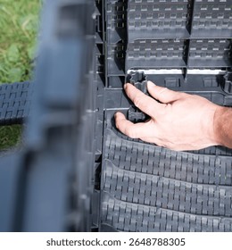 Assembling a plastic modular structure outdoors.  A hand connects components.