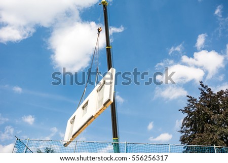 Assembling a prefabricated house - wall is hanging on a crane