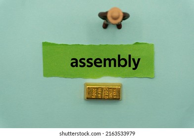 assembly.The word is written on a slip of paper,on colored background. professional terms of finance, business words, economic phrases. concept of economy.