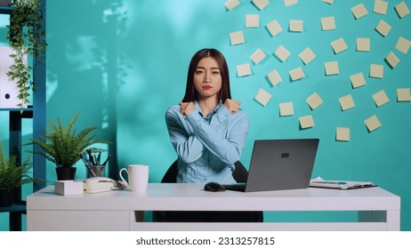 Assertive asian employee adamant about saying no, confident in her stance, holding two crossed arms in X sign. Upset but determined office clerk rejecting stressful work conditions
