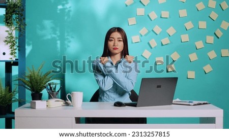 Assertive asian employee adamant about saying no, confident in her stance, holding two crossed arms in X sign. Upset but determined office clerk rejecting stressful work conditions