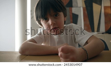 Assertive child hits table surface with hand. 5 year old boy demanding attention while looking at camera, close-up face and fist