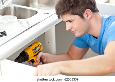 Assertive Man Holding A Drill Repairing A Kitchen Sink At Home