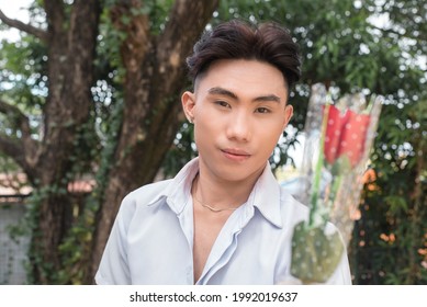 An assertive suitor hands out a single rose. A confident young asian man in love. POV of date. Courtship concept.