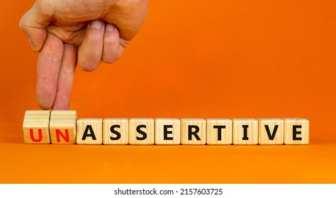 Assertive or unassertive symbol. Businessman turns wooden cubes and changes concept words Unassertive to Assertive. Beautiful orange background. Business assertive or unassertive concept. Copy space.