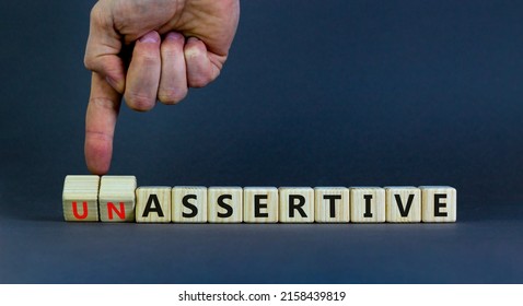 Assertive or unassertive symbol. Businessman turns wooden cubes and changes concept words Unassertive to Assertive. Beautiful grey background. Business assertive or unassertive concept. Copy space. - Shutterstock ID 2158439819