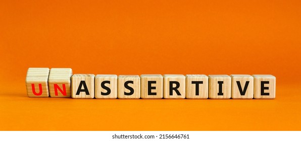 Assertive or unassertive symbol. Turned wooden cubes and changed concept words Unassertive to Assertive. Beautiful orange background. Business and assertive or unassertive concept. Copy space.