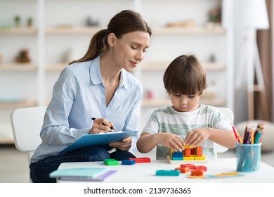 Assessment of kids mental development. Professional woman psychologist watching little boy playing with logical game, evaluating his readiness for preschool, free space