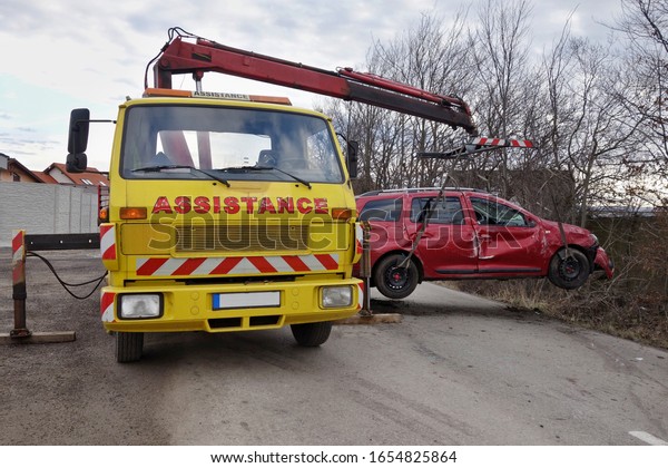 Assistance car lifts and loads a car after an\
accident. Tow truck with equipped hydraulic manipulator. Сar\
accident concept.