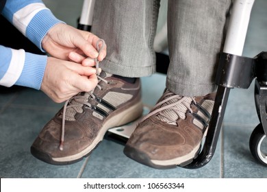 assistance for a disabled man in wheelchair, tying shoes - Shutterstock ID 106563344
