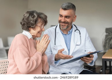 Assistance male doctor explaining results of examination to senior elderly woman after treatment and checkup. Caregivers smile to encourage and care for patient - Powered by Shutterstock