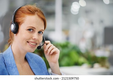 Assistance Is A Phone Call Away. Shot Of An Attractive Red Headed Female Wearing Head Sets In An Office Setting.