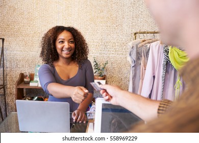 Assistant At Clothes Shop Taking Credit Card From Customer