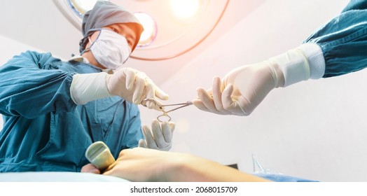 Assistant Hands out Instruments to Surgeons During Operation. Surgery and emergency concept
