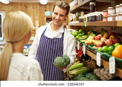 Assistant Helping Customer At Vegetable Counter Of Farm Shop