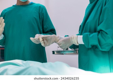 Assistant passing instrument to surgeon. Team of surgery doctor in Operating Room hold hands scalpel surgical blade give to Surgeons During Operation. - Powered by Shutterstock