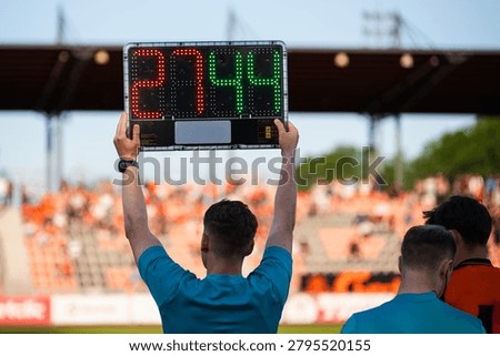 Assistant referee displaying substitution board during a soccer match with stadium crowd in the background