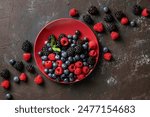 Assorted of berries on red plate. Raspberry, blackberry, and blueberry on black background