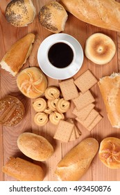 Assorted bread rolls, cookies and coffee cup at wooden plank background. Directly Above.
