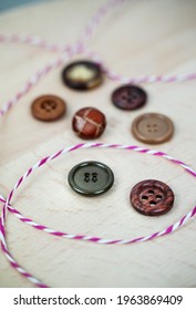 Assorted Buttons And Striped String On Light Wood