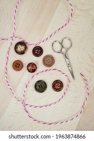 Assorted Buttons, Striped String And Scissors On Light Wood Background