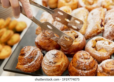 Assorted cakes on the table. Catering at events. A gloved hand of a worker takes a loaf. Close-up.