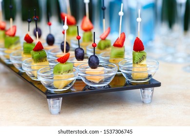 Assorted Canapes Of Fruit And Cheese On A Glass Platter On The Background Of Glasses And Champagne. Catering