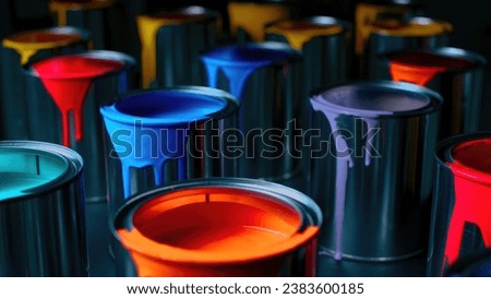 Assorted cans of paint in different colors set against a dark background.
