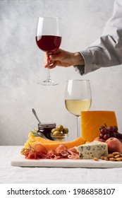 Assorted cheese, ham, fruit, jam, bread sticks, nuts. Cheese platter. Marble tray on table covered with linen tablecloth. Side view 