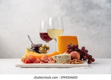 Assorted cheese, ham, fruit, jam, bread sticks, nuts. Cheese platter. Marble tray on table covered with linen tablecloth. Side view  - Powered by Shutterstock