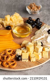 Assorted Cheese On A Wooden Plate On A Gray Background With A Copy Space. Wine Appetizer With Honey, Grapes, Pretzels And Walnuts On A Round Platter. Vertical Orientation, Close-up, No People