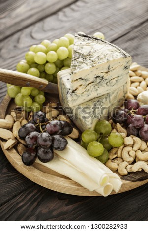 Assorted Cheese Wooden Plate Surface with Fruit and Nuts, Cheese with Mold, Noble cheeses, Goat, Sheep, Cow Cheese, Dairy Products, Calcium, Vitamins and Minerals, Wholesome, Grapes, Cashew, Almond