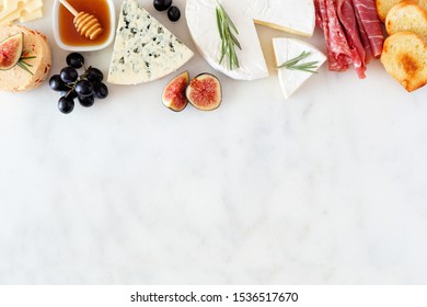 Assorted cheeses and meat appetizers. Top border, overhead view on a white marble background with copy space. - Powered by Shutterstock