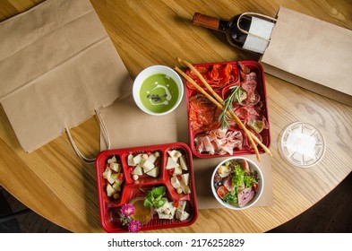 Assorted cheeses with nuts and honey. Assorted sausages and jerky. Salad with lettuce, cherry tomatoes and tuna. Food for delivery. Dishes in plastic boxes. Food for a company, holiday or picnic.