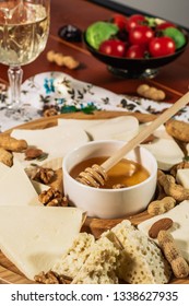 Assorted Cheeses On Round Wooden Board Plate Served With White Wine Guda Cheese, Cheese Grated Bark Of Oak, Hard Cheese Slices, Walnuts, Grapes, Crackers, Honey, Sulguni, Light Wood Background