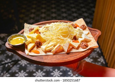 Assorted cheeses in various shapes and sizes. Waiter serving cheese platter in a bowl. In restaurant or diner. Eating out concept.