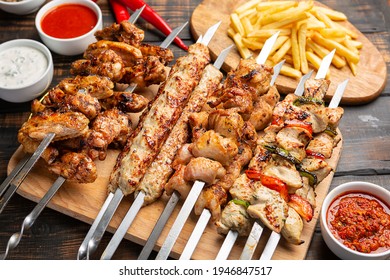 Assorted chicken kebabs with French fries and sauce on dark wooden background - Powered by Shutterstock