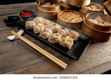 Assorted chinese dim sum dumpling on the plate with bamboo wooden basket bowl and chopstick with sauce on wooden table. Food for breakfast, lunch or dinner. Chinese Or Lunar New Year decoration