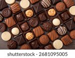 Assorted chocolates in a box, with truffles, squares, and bars in dark, milk, and white varieties.