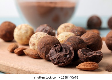 assorted chocolates. Candy balls of different types of chocolate on a wooden board on a blue wooden table. almond and cocoa