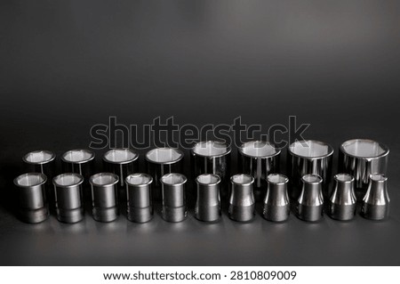 Assorted chrome socket wrench sockets arranged by size on a dark background with clean composition and ample copy space.