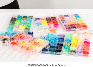 Assorted clay bead boxes neatly arranged on a white table, awaiting a creative kids' craft project.