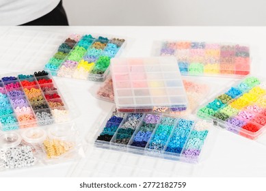 Assorted clay bead boxes neatly arranged on a white table, awaiting a creative kids' craft project.