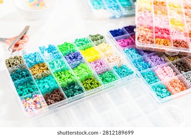 Assorted clay bead boxes neatly arranged on a white table, awaiting a creative kids' craft project