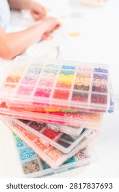 Assorted clay bead boxes neatly arranged on a white table, awaiting a creative kids' craft project.
