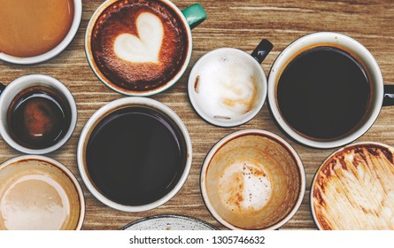 Assorted coffee cups on a wooden table - Shutterstock ID 1305746632