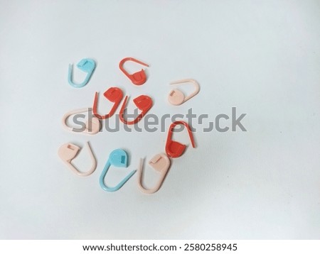 Assorted colored plastic stitch markers used for knitting and crocheting on a white background