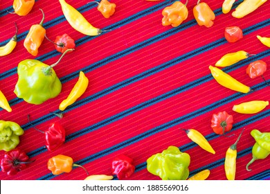 Assorted Colorful Chili Peppers In A Frame Pattern On A Red Table Cloth (Overhead)